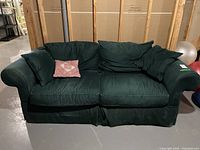 Front view of the dark green couch with a decorative pillow on the left side cushion.