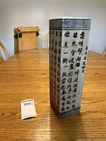 Front angled view of decorative umbrella stand showing Chinese script and Greek key border design.
