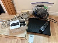 Samsung Blu-ray player with remote, Apple TV with remote, power strip, and HDMI cables on floor