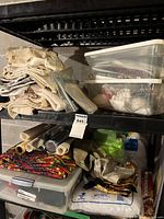 Image showing stacked plastic containers and bins filled with assorted fabric rolls, batting, and other craft materials on shelving unit.