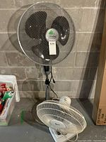 Full view of both fans side by side on the floor against a wall, showing their size difference.