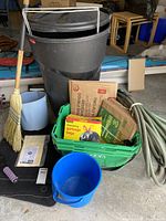 Large trash can, green bin, buckets, broom, garden hose, and bags
