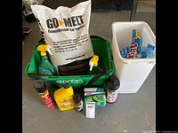 Photo of ice melt collection including large Go Melt bag, green plastic tote with spray bottles, insecticide, motor oil, antifreeze, organic fertilizer, and ice traction items.