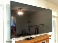 Front view of 55" TV on mantel with remote and power cord placed below