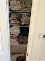 Closet view with folded towels and linens on multiple wire shelves