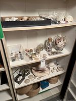 Shelving unit with seashells, glass jars filled with shells, and woven baskets underneath.