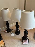 Photo showing all three black base table lamps with white shades arranged on carpeted floor; lamps are about 19 inches tall each