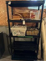 Front angled view of the black plastic utility shelf loaded with various items but contents not included in sale.