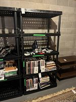 Front view of black plastic shelving unit with four shelves. Various items on shelves not included in sale.