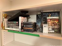 Shelf with stacked Xbox 360 and PC game cases, titles include Halo 3, LEGO Indiana Jones, Half-Life 2, Ghost Recon