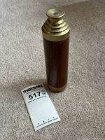 The telescope in its collapsed state, showing the wooden body with brass accents and the lens cap attached.