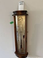 Full front view of wood and glass wall barometer showing entire case and instruments