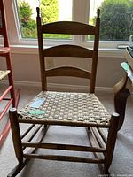 Front view of wooden nursing chair with slatted back and woven seat in natural wood finish.