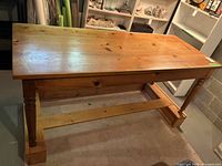 Wooden table side view showing natural wood finish, turned legs, and base stand.