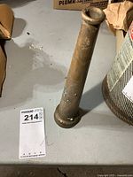 Side view of brass fire hose nozzle showing tapered shape and surface wear.