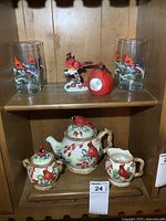 Full view of the ceramic teapot set with cardinal bird motif along with matching glasses, solar bird light, and figurine, displayed on wooden shelves.
