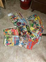 Collection of colorful vintage comic books laid out on carpet showing a variety of titles including Superman, Archie, Mad House, The Beagles