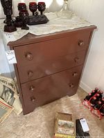 Front view of the vintage painted wooden 4 drawer dresser showing round wooden knobs and overall brown finish.