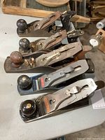 Five vintage hand planes arranged in a row showing overall condition and size differences.