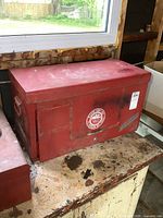 Closed red MAC Tools metal toolbox on a worn wooden surface, showing logo and aged wear.