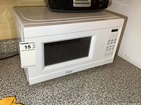 Front view of the white Master Chef microwave on a speckled countertop showing the keypad and door window.