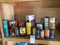 Vintage oil cans and tire repair kits arranged on wooden shelf with visible labels and boxes
