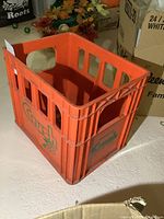 Orange plastic crate with 'Crush' branding on the side, shows overall front and side view of the crate on a white surface under indoor lighting.