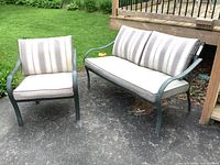 Photo showing the loveseat and matching chair placed outdoors on a patio surface, with grass and outdoor steps in the background.