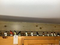 Full view of the 12 small porcelain bird figurines lined up on a wood ledge showing their size and variety.