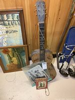 Overview of the lot showing the guitar, signed photo, and book in front of wood paneling and paintings