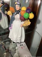 Front and side view of Royal Doulton porcelain figure Biddy Penny Farthing with colorful balloons and basket of flowers.