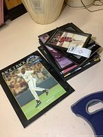Stack of framed vintage sports photos and the Blue Jays 1993 World Series book on a table