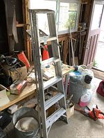 Full view of the aluminum step ladder showing five steps and A-frame structure in a workshop environment.