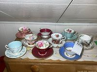 Full set of nine assorted teacups with matching saucers in various colors and floral designs