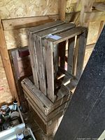 Stack of 4 wooden crates including 2 larger tomato crates and 2 smaller crates against wooden wall