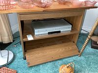 Photo of the silver Toshiba VCR/DVD combo player inside the wooden stand, showing size and condition.