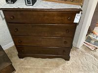 Front view of vintage solid wood 4 drawer dresser with dark brown finish and wooden knobs.
