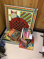 Photo shows multi-game board with crokinole, checkerboard and other game patterns alongside various boxed vintage games including Beverly Hillbillies puzzle.