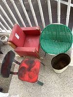 Shows vintage red vinyl child's rocker chair, green plastic wicker outdoor chair, older wooden child's chair with red painted seat, and metal trash can, all with visible wear.