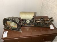 Side view of metal horse-drawn carriage with clock and canopy, showing four horses and carriage body with clock face.