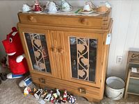 Front view of vintage solid wood sideboard with small top drawer and larger drawer below, featuring decorative glass door panels with vine and leaf design.