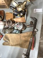 Photo of welding gauges, cutting torch, and glove on table showing condition and quantity.