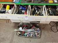 Top view showing assorted hand tools, loose hardware items in trays and tubs, organized in drawers and a tray below