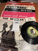 Photo showing Beatles 45 RPM record and cover with 'Twist and Shout' and 'She Loves You' labels and Beatlemania album cover.