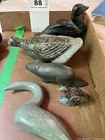 Overview of five carved animal and bird sculptures in cardboard tray