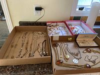 Overall lot showing multiple cardboard boxes filled with costume jewelry including necklaces, bracelets and earrings.