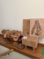 Photo showing all wood items together including two carved panels, burl wood piece, and wooden block with legs