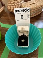 Ring inside a blue plastic bowl with white vintage box and auction tag visible