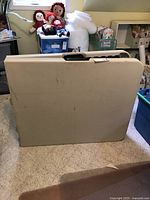 Photo of the folded beige folding table showing handle and surface marks