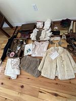 Full view of the lot showing the fur coat, clothing items, various purses, gloves, and wooden jewelry box along with decor items spread on wooden floor